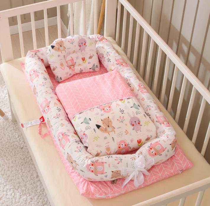 Baby crib with floral and animal-patterned bumper and pink blanket