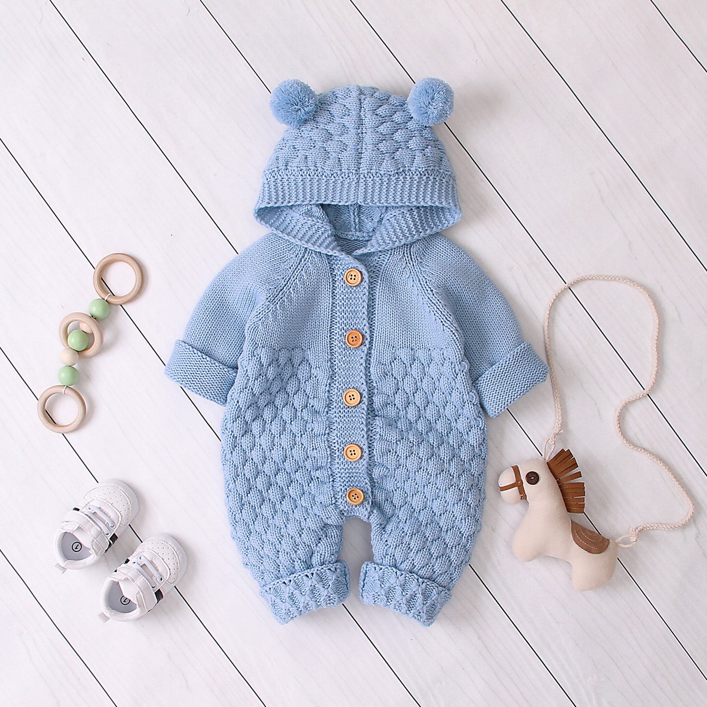 Close-up of baby hooded knit jumpsuit showing soft fabric and button details