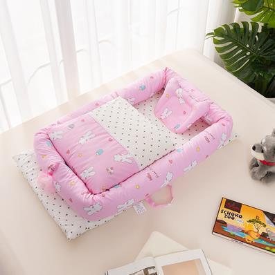 Pink baby crib with cartoon design on a light-colored surface