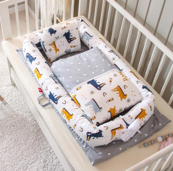 Baby crib with dinosaur-patterned bumper and gray mattress
