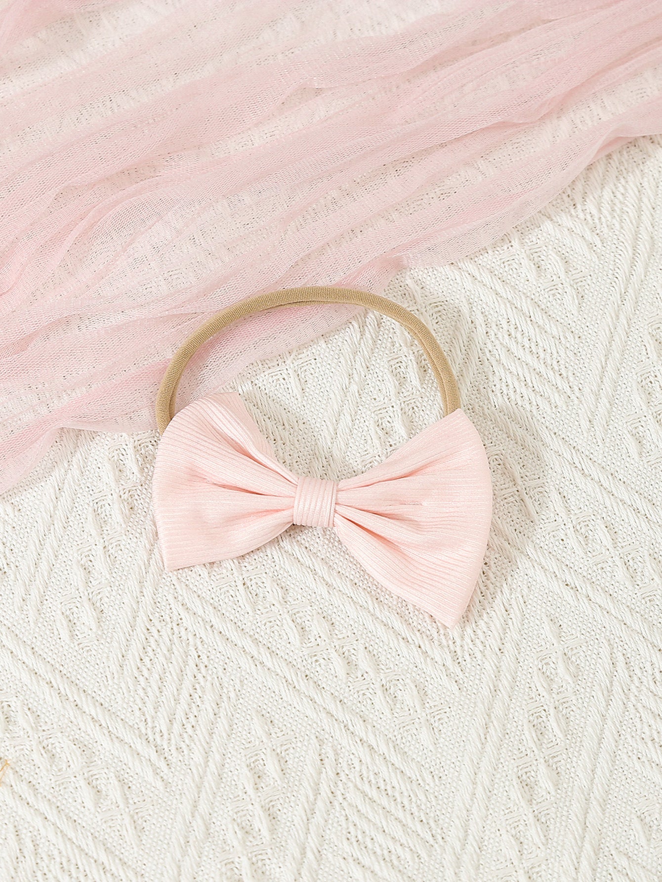 Pink bow headband on a textured pink and white background