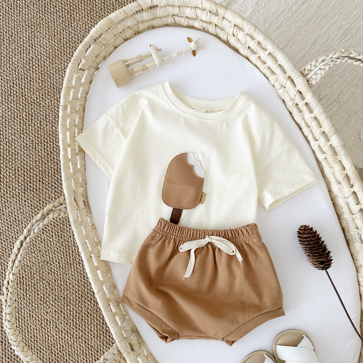Children's outfit with white shirt and brown shorts on a textured surface