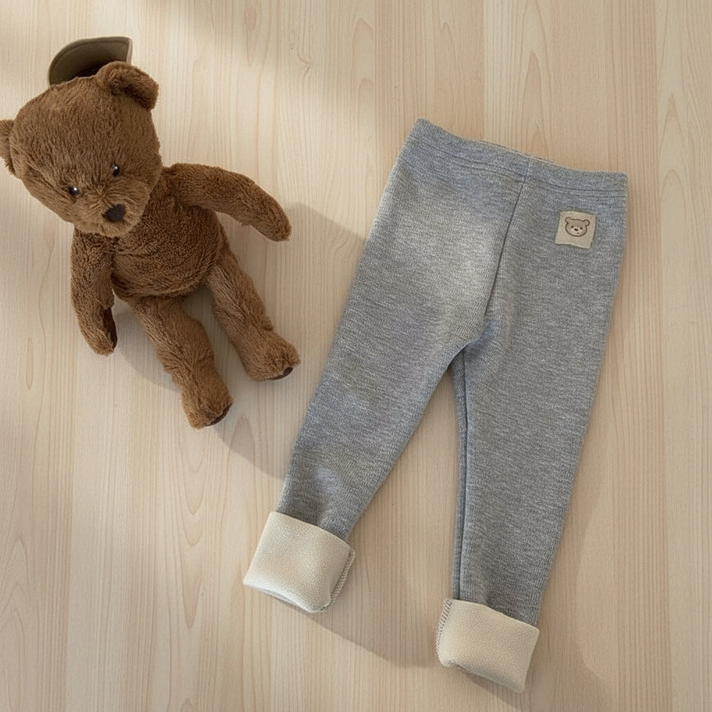 Brown teddy bear and gray baby leggings with beige cuffs on a white background