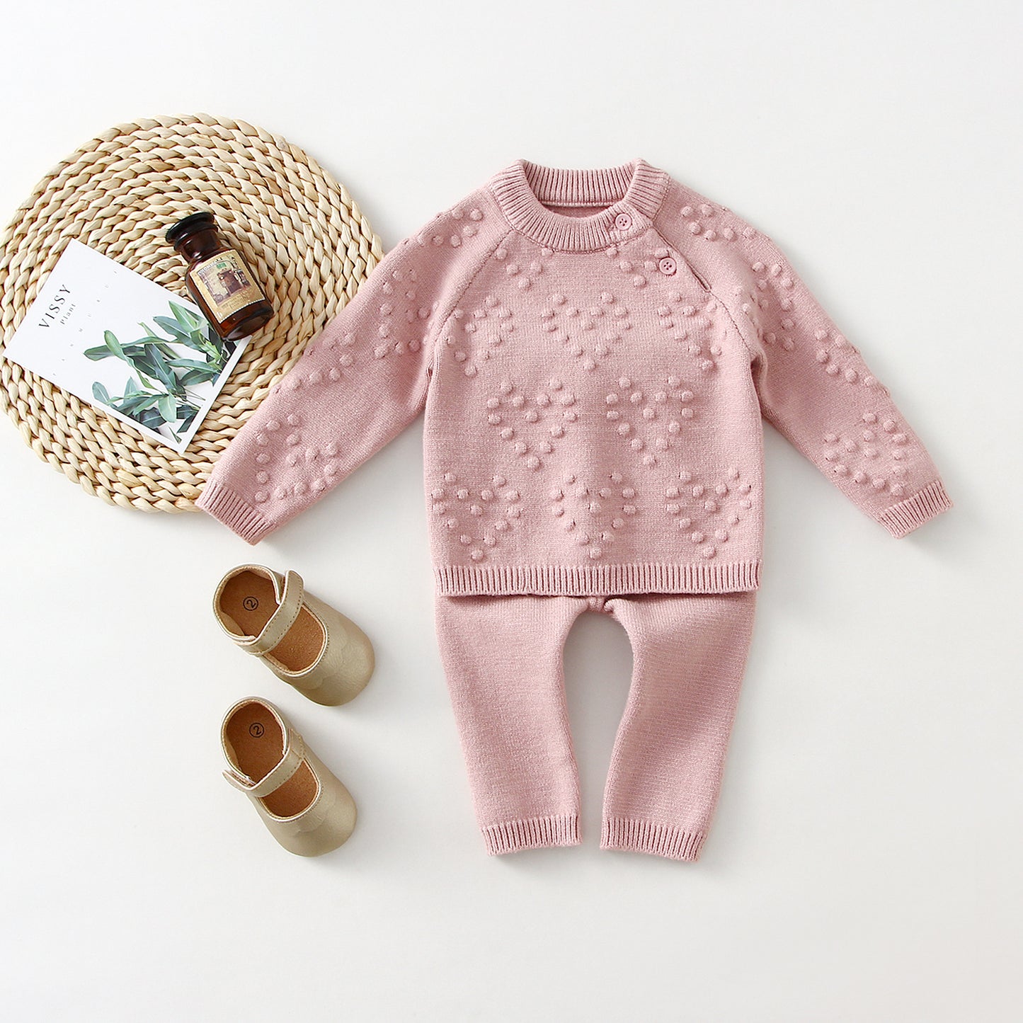 Pink knitted outfit with matching shoes on a white background