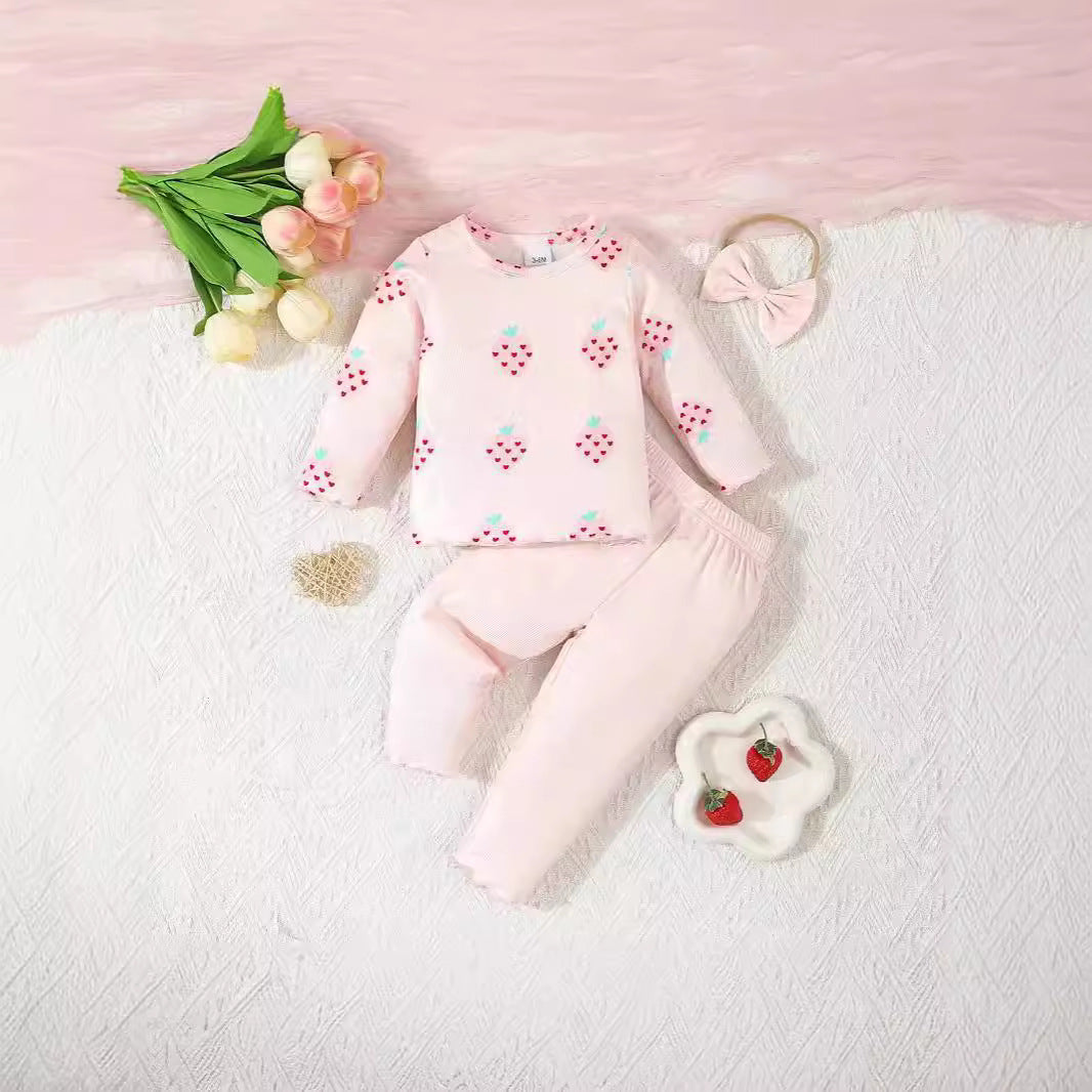 Baby outfit with pink floral pattern on a white blanket with decorative items.