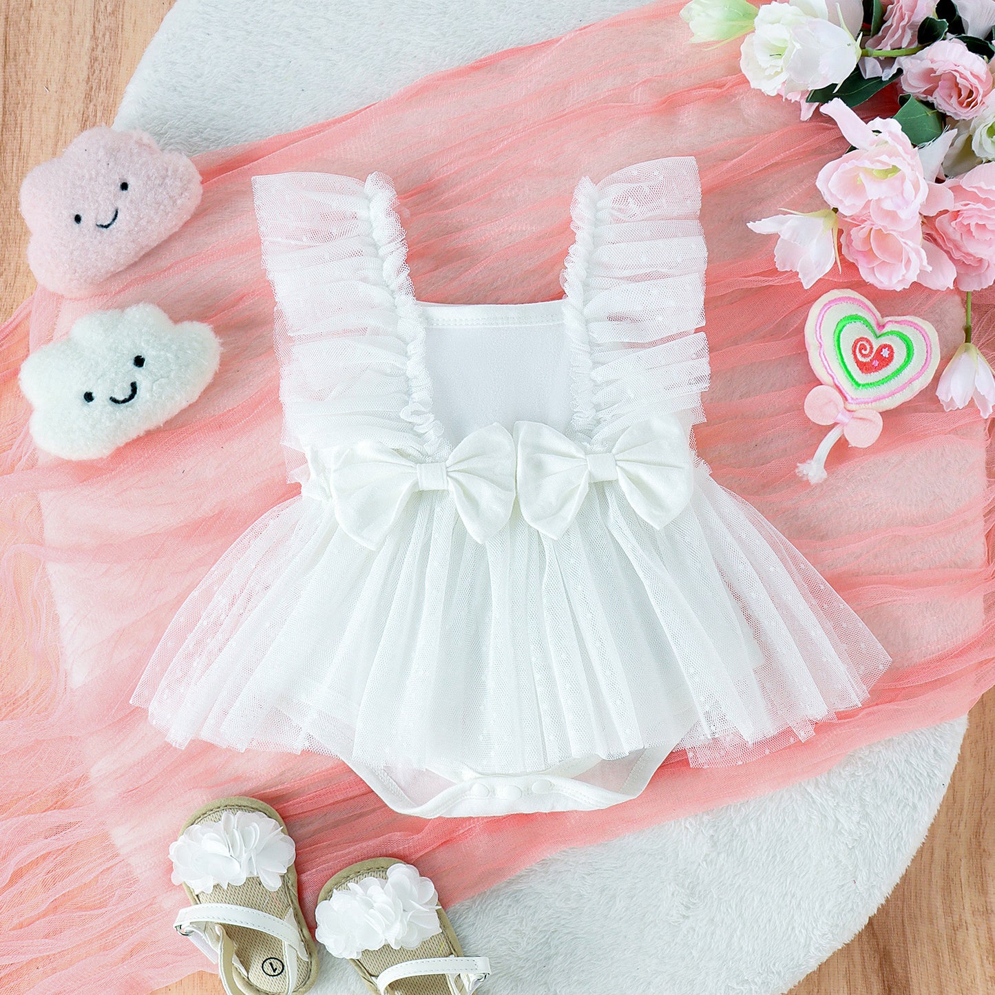 White dress with ruffles, pink tulle, and decorative items on a wooden surface