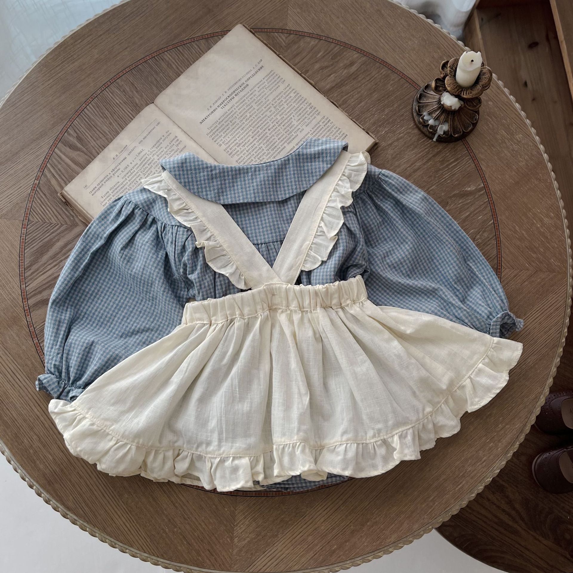 Children's blue checkered dress with white ruffled skirt on a wooden surface.