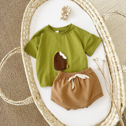 Green shirt with a brown bear design and brown shorts on a textured surface