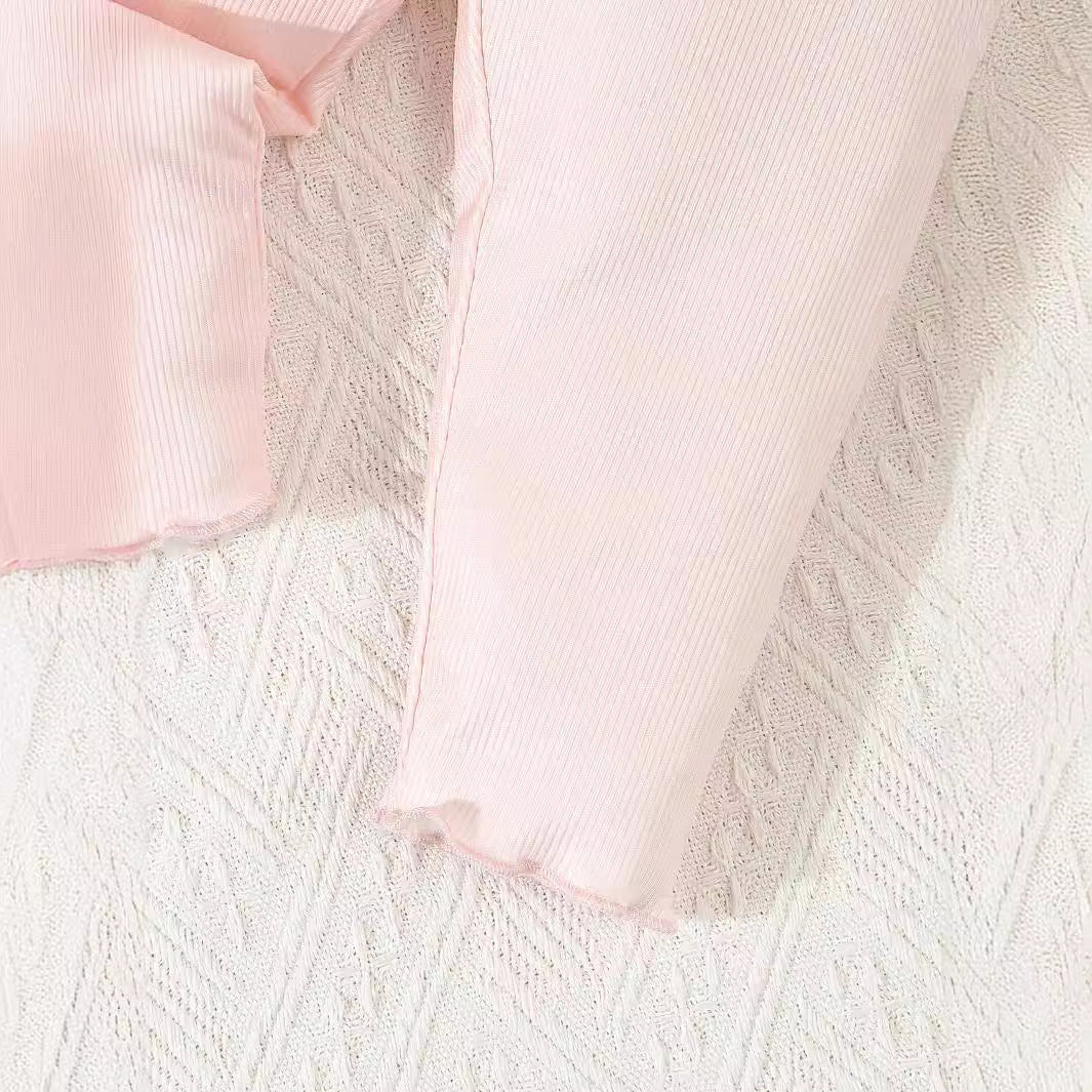 Close-up of pink ribbed fabric on a textured white surface